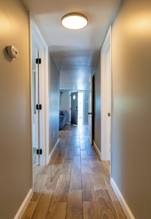 Ein Flur mit einer Leuchte, einem Thermostat und einer Tür zu einem Zimmer mit Blick.