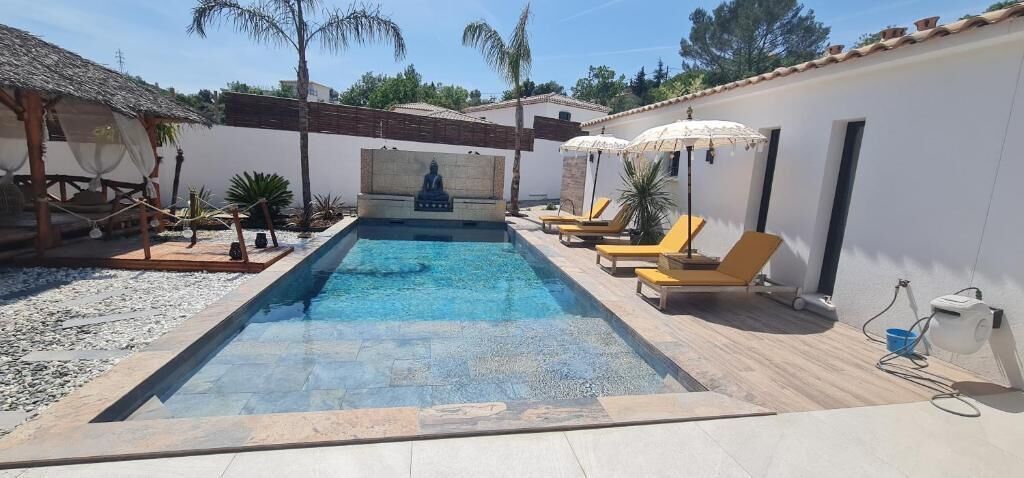 A swimming pool with lounge chairs, a statue, and a small garden area.