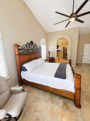 A bedroom with a wooden bed, a ceiling fan, a chair, and an arched doorway. - Infrared Sauna, Mountain View’s,Golf,Hiking and infrared red light therapy. (Scottsdale)