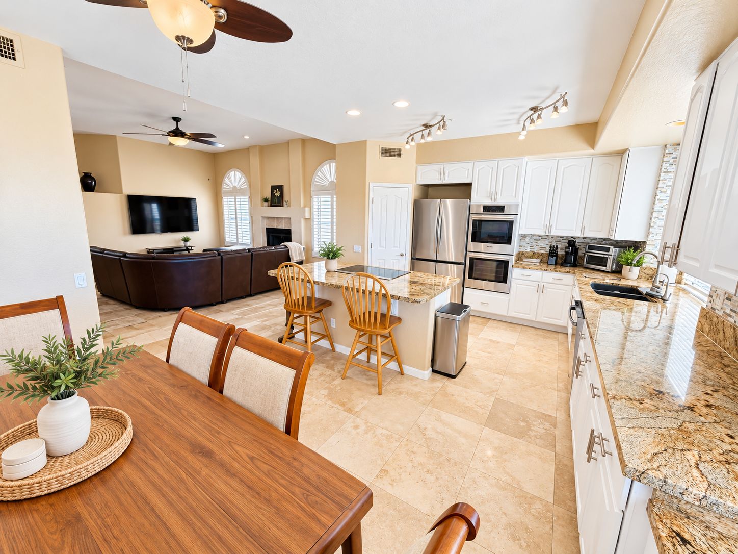 A modern kitchen with a central island, built-in appliances, and a dining area with a wooden table and chairs.
