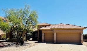 A residential building with a garage, a driveway, and a tree in the foreground. - Infrared Sauna, Mountain View’s,Golf,Hiking and infrared red light therapy. (Scottsdale)