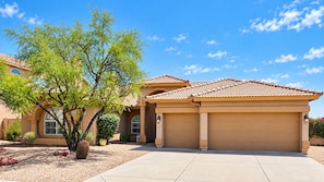 A residential house with a tiled roof, a garage, and a landscaped front yard with a tree and a cactus. - Mayo wellness retreat Pool, sauna + red light (Scottsdale)