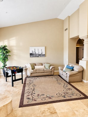 A living room with a foosball table, two sofas, a coffee table, and a large rug. - Mayo wellness retreat Pool, sauna + red light (Scottsdale)