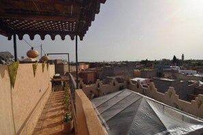 Una terraza en la azotea con vistas a la ciudad, una pérgola y plantas en macetas.