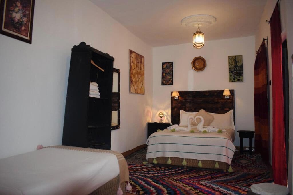 A bedroom with a bed, a bedside table, a lamp, and a wall-mounted artwork.