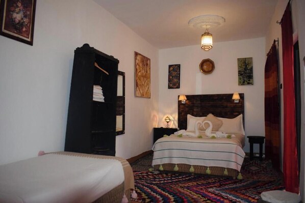 A bedroom with a bed, a bedside table, a lamp, and a wall-mounted artwork. - Riad Vis Ta Vie (Marrakech)