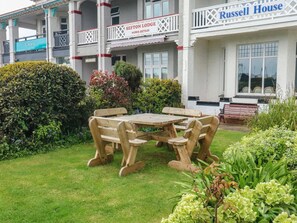 Ein Garten mit einem Holztisch und Bänken, umgeben von verschiedenen Pflanzen und Sträuchern.
