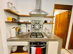 A compact kitchen with a gas stove, oven, and a coffee maker. - Amazing 3-bedroom villa with private pool, 400m from beach & restaurants (Las Terrenas)