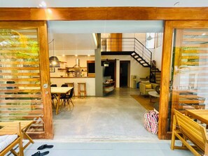 Un vaste espace de vie comprenant une table à manger, des chaises, un canapé et un escalier menant à l’étage supérieur.
