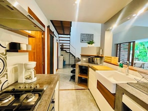 A modern kitchen with a gas stove, coffee maker, and a view of a staircase leading to a balcony. - Amazing 3-bedroom villa with private pool, 400m from beach & restaurants (Las Terrenas)