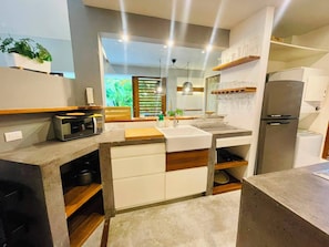 A modern kitchen with a central island, built-in appliances, and a view of greenery outside. - Amazing 3-bedroom villa with private pool, 400m from beach & restaurants (Las Terrenas)