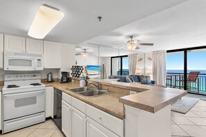 A modern kitchen with a central island, a dining area with a view, and a ceiling fan. - 🌴Gulf Front~Pools~Onsite Restaurant~Balcony~Sauna~1BR SunDestin 1405🌴 (Destin)