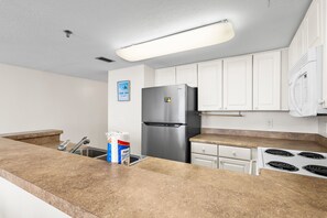 A kitchen with a stainless steel refrigerator, a sink, and a stove. - 🌴Gulf Front~Pools~Onsite Restaurant~Balcony~Sauna~1BR SunDestin 1405🌴 (Destin)