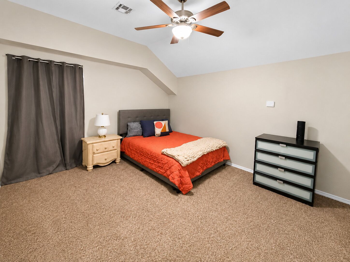 A bedroom with a bed, nightstand, dresser, and ceiling fan.