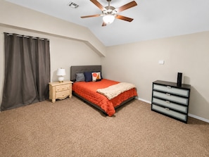 A bedroom with a bed, nightstand, dresser, and ceiling fan. - Modern Tulsa Haven  Near Jenks (Tulsa)