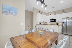 Eine moderne Küche mit weißen Schränken, einem Edelstahlkühlschrank und einem Holzespeisetisch mit Stühlen.