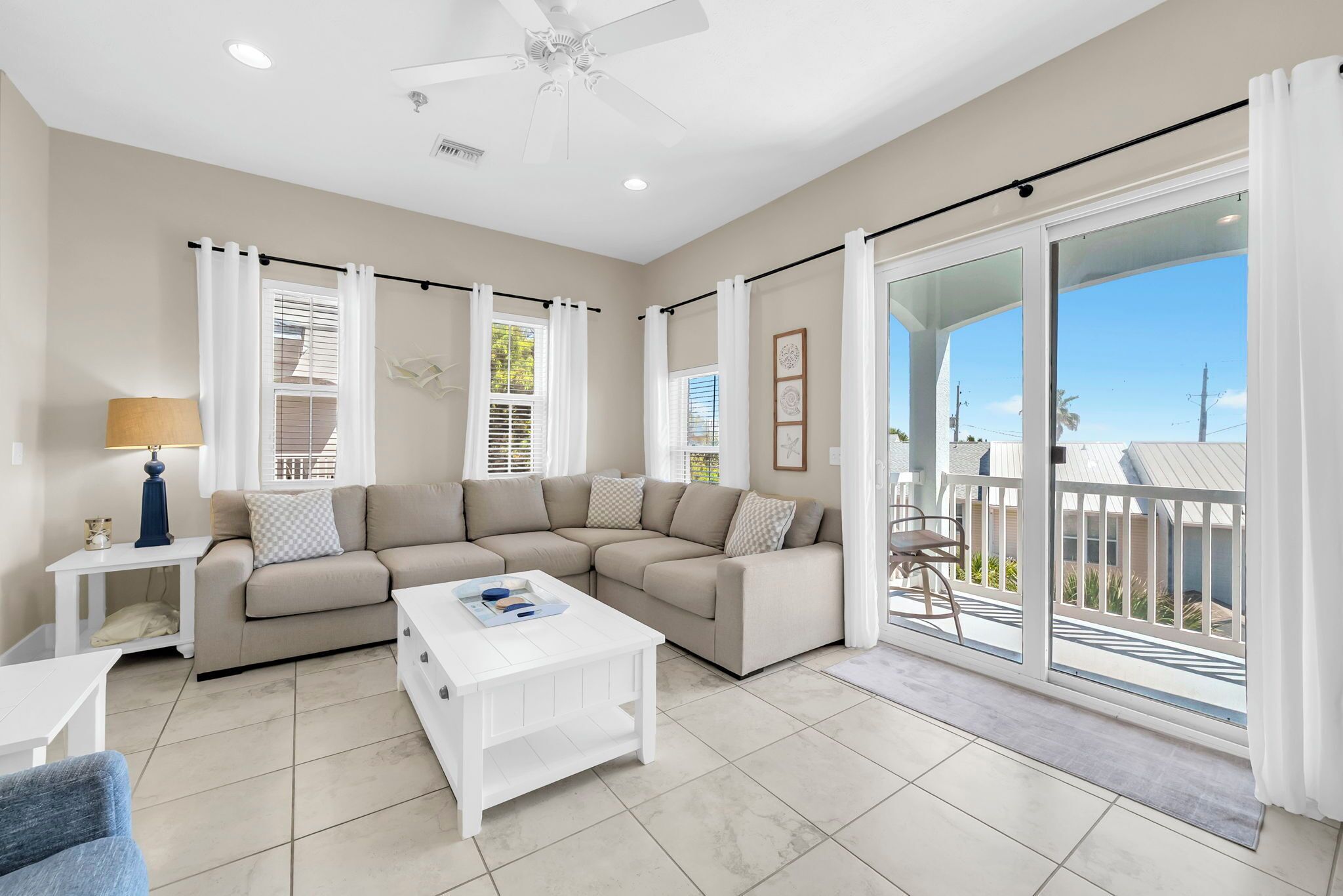 A modern living room with a sectional sofa, a white coffee table, and a balcony with a view.