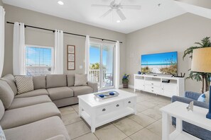 Ein modernes Wohnzimmer mit Sofa, Couchtisch, Fernseher und einem Balkon mit Blick.