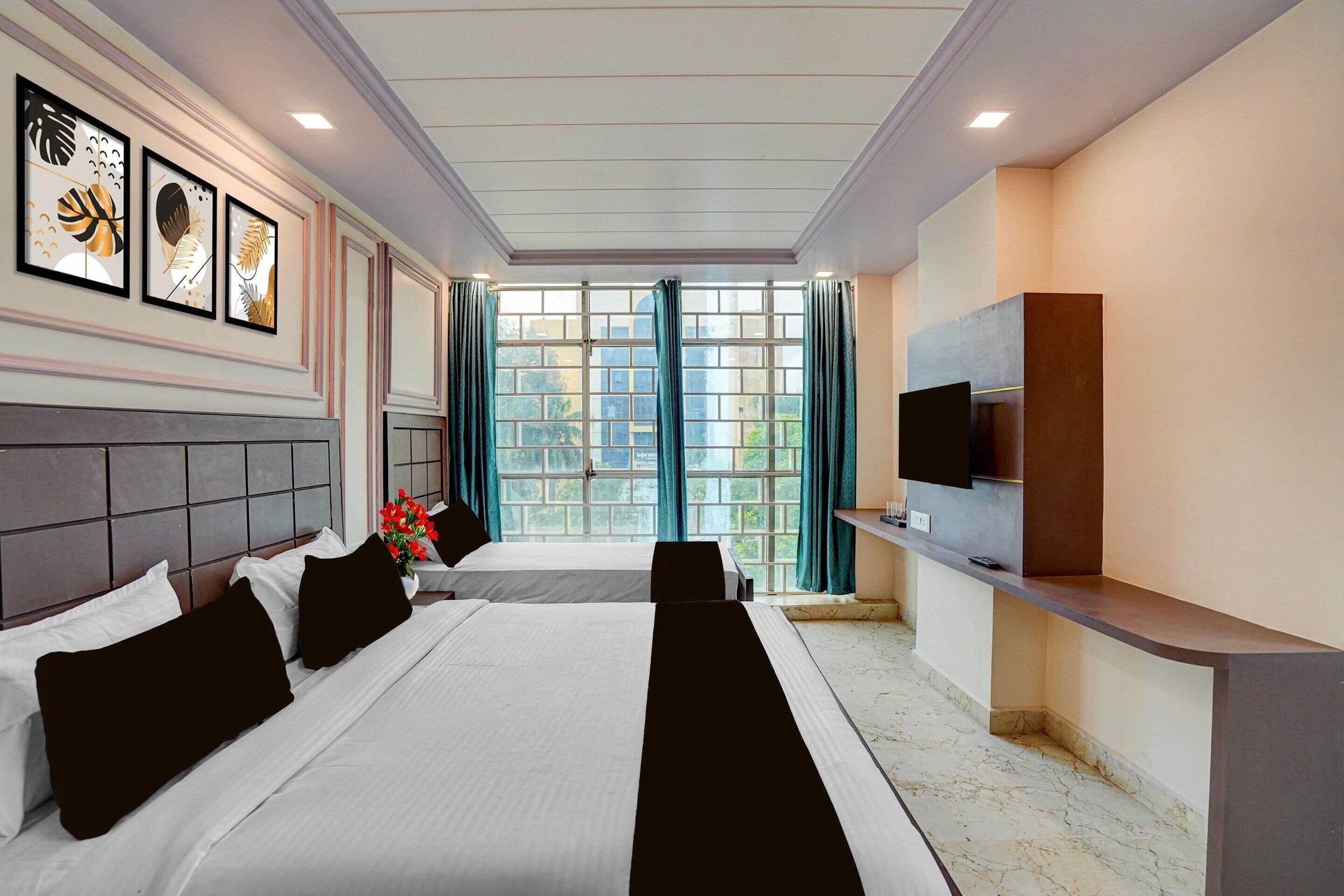 A hotel room with a large bed, a TV, and a window with curtains.