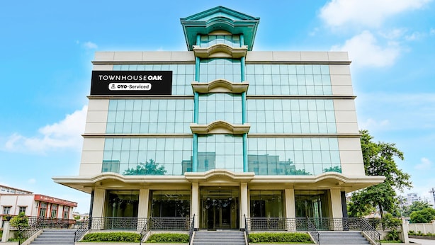 A multi-story building with a sign reading 'TOWNHOUSE OAK' and 'YO-Service.' - Premium Room Mauji's (Prayagraj)
