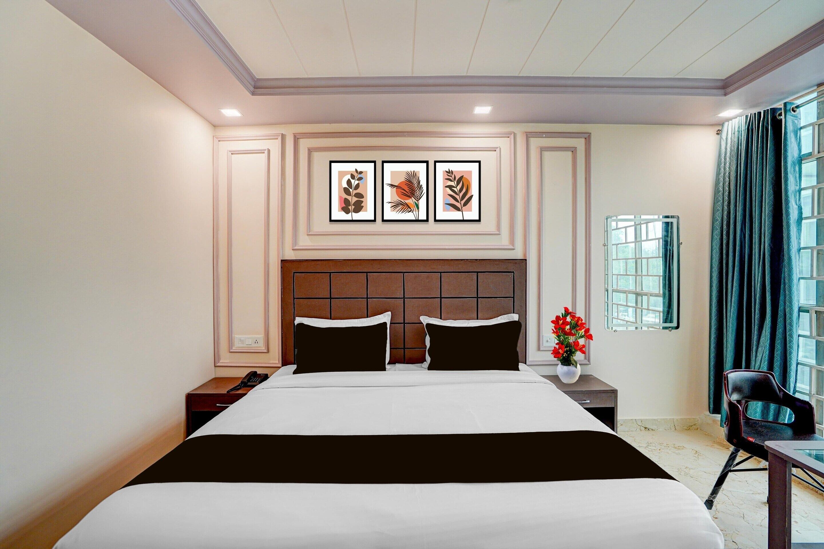 A hotel room with a large bed, a nightstand, a chair, a window with curtains, and artwork on the wall.