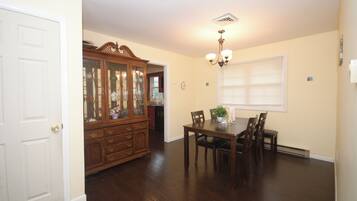 A dining area with a wooden table and chairs, a cabinet with glass doors, and a ceiling light fixture.