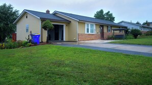 A single-story residential house with a front porch, a small attached garage, and a well-maintained lawn.