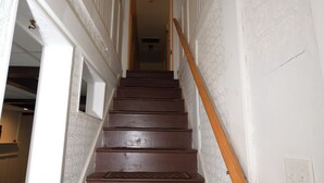 A staircase with wooden steps and a handrail, leading to an interior space.