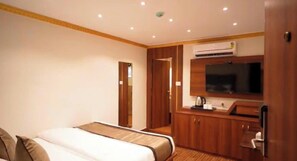 Habitación de hotel con cama, televisión y una pequeña cocina.