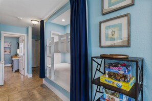A room with a blue wall, a white door, and a shelf with board games. - 🏖️The Peachy Pelican~Gulf Views~Hot Tub~Private Beach Access Steps to Dining🏖️ (Destin)