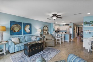 A living room with a sofa, a coffee table, and a dining area with chairs. - 🏖️The Peachy Pelican~Gulf Views~Hot Tub~Private Beach Access Steps to Dining🏖️ (Destin)