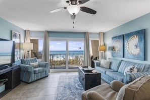 A living room with a television, striped sofas, a ceiling fan, and a view of the beach. - 🏖️The Peachy Pelican~Gulf Views~Hot Tub~Private Beach Access Steps to Dining🏖️ (Destin)