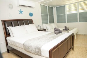 Ein Schlafzimmer mit einem großen Bett, einem Nachttisch, einer Fensterbank und einem Fenster mit Jalousien.