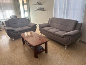 Ein Wohnzimmer mit zwei grauen Sofas, einem Holztisch und einem Bücherregal mit Dekoration.