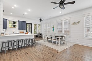 Una cocina amplia con una isla central, taburetes de bar y un comedor con mesa y sillas.