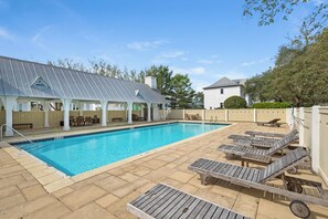 Ein Schwimmbecken mit Liegestühlen und einer überdachten Terrasse.