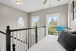 Ein Zimmer mit einem Bett, einem Fenster mit Blick, einem Deckenventilator und einer Treppe.
