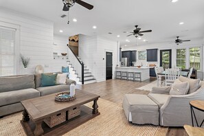 A spacious living area with a sofa, coffee table, and a kitchen in the background. - 🚲Willow & Waves | Golf Cart, 4 Bikes, Pool, Near Beach🏊 (Inlet Beach)