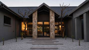 A modern building with a stone facade, large glass windows, and a gravel driveway.