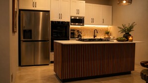 A modern kitchen with a built-in island, stainless steel appliances, and a pendant light.