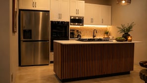 A modern kitchen with a built-in island, stainless steel appliances, and a pendant light. - Villa Thula (Hoedspruit)