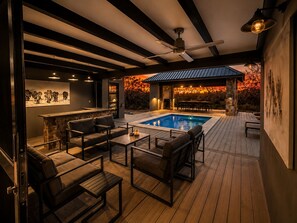 A poolside area with a bar, seating, and a view of a sunset.