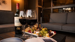 Una botella de vino Merlot, dos copas de vino y una tabla de fiambres sobre una mesa.
