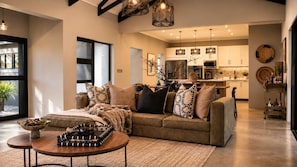 A modern living room with a sofa, coffee table, and decorative pillows. - Villa Thula (Hoedspruit)
