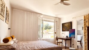 Habitació d'hotel amb un llit, una taula de treball, una cadira i un televisor.