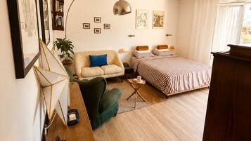 A bedroom with a bed, a desk, a chair, a ceiling fan, and a window.