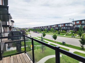 A residential area with modern apartment buildings, a street with parked cars, and a clear sky. - The Edmonton Nest (Edmonton)