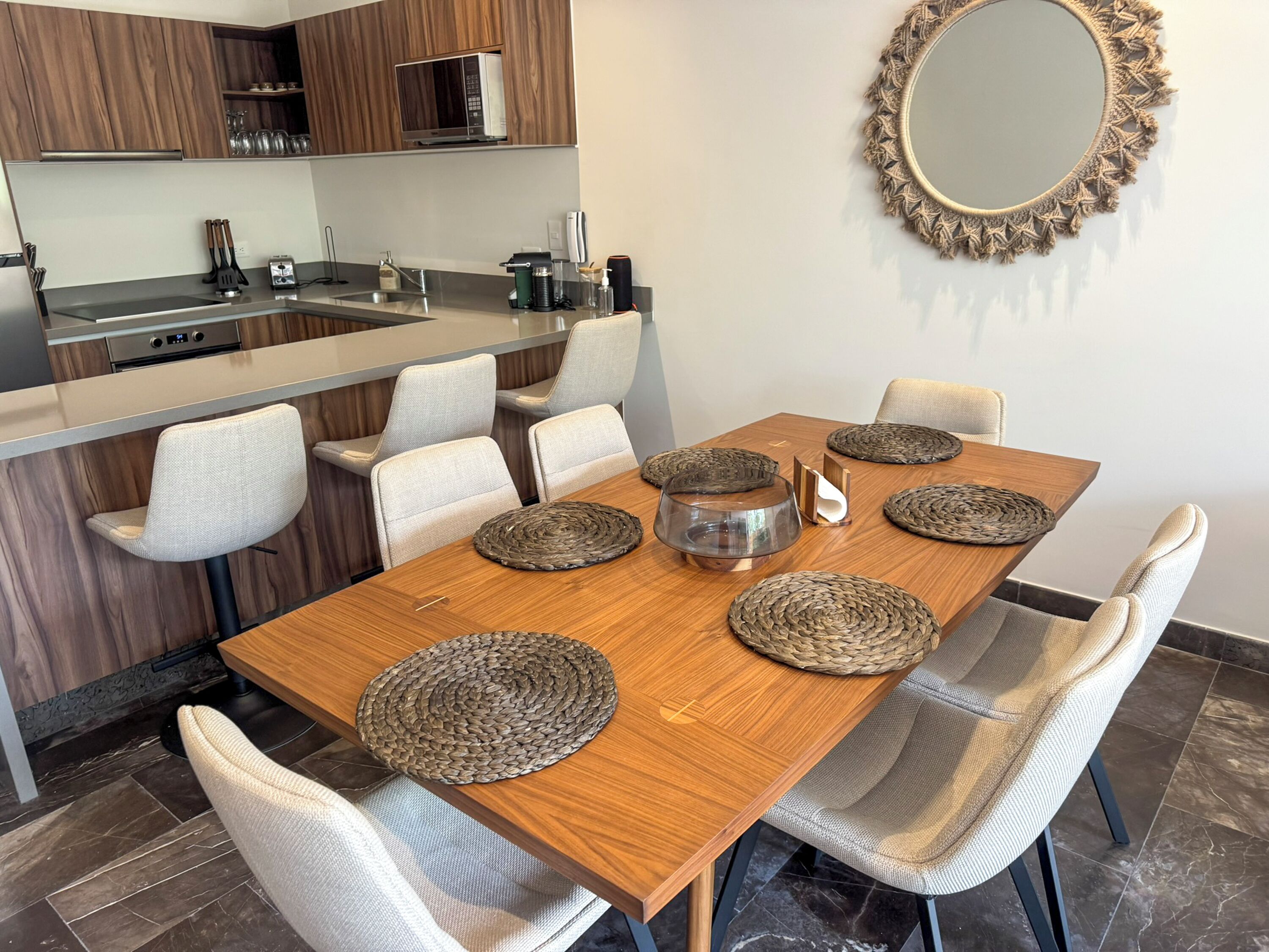 Een moderne keuken met een houten eettafel, zes stoelen en een magnetron boven het aanrecht.