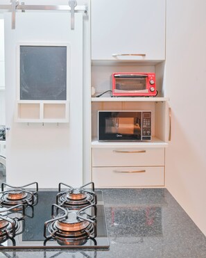 Eine Küche mit einem Gasherd, einem roten Mini-Backofen und einer schwarzen Mikrowelle.