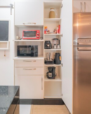 Eine kleine Küche mit Mikrowelle, Kaffeemaschine und Kühlschrank.